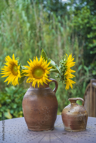 Fototapeta Naklejka Na Ścianę i Meble -  Bouquet of yellow sunflowers in rustic clay jug outdoors