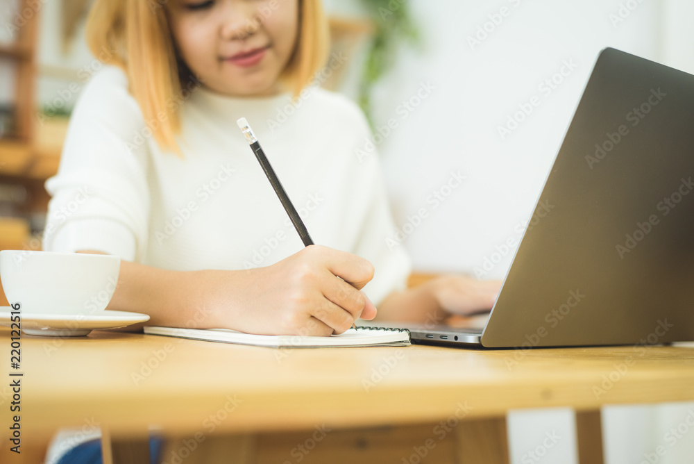 Beautiful young smiling asian woman working on laptop while sitting in a living room at home. Asian business woman working in her home office. Enjoying time at home. Beautiful young smiling asian woman working on laptop while sitting in a living room at home. Asian business woman working in her home office. Enjoying time at home.