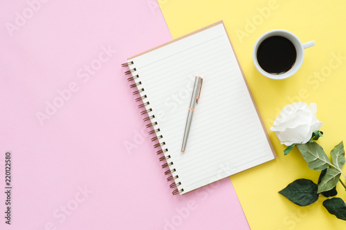 Creative flat lay photo of workspace desk. Top view office desk with mock up notebooks, flower, coffee cup and copy space on pastel color background. Top view with copy space, flat lay photography.