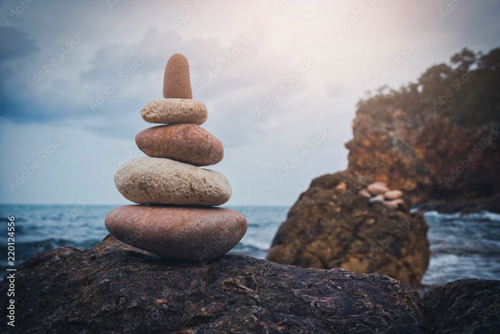 Fototapeta premium Stone tower on the rock near pebble beach. Vintage tone.