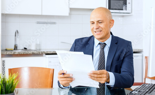 Portrait of confident manager sitting at desk and holds a folder of documents © JENOCHE