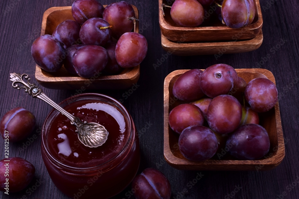 Obraz premium Plum jam in a glass jar surrounded by the berries