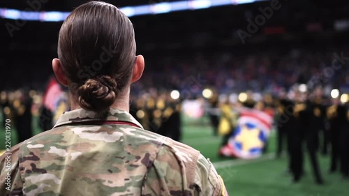 Female army soldier watching a halftime show of a football game√Ç