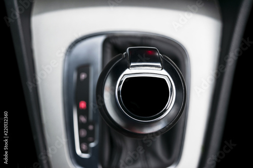 Automatic gear stick of a modern car. Maodern car interior details. Close up view. Car detailing. Automatic transmission lever shift. Black leather interior with stitching. © Aleksei