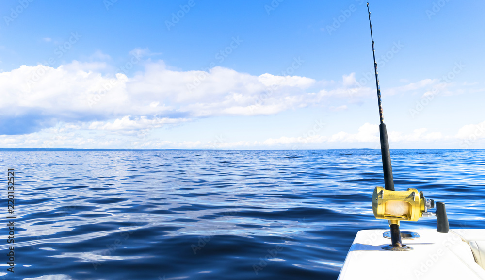 Fishing rod in a saltwater private motor boat during fishery day in blue ocean. Successful fishing concept