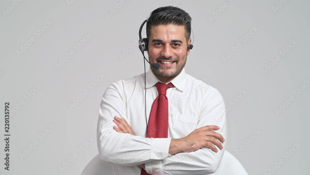 Customer service operator portrait. Young indian man with red tie and headphone, greeting confident pose in front of camera. Customer service call center concept.