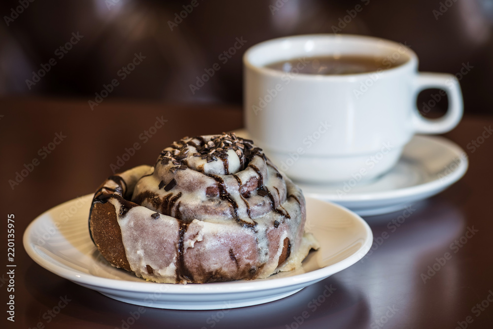 Chocolate cake on a plate before a cup of tea Chocolate cake on a plate before a cup of tea