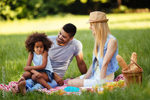 Offended little girl sitting with parents on picnic