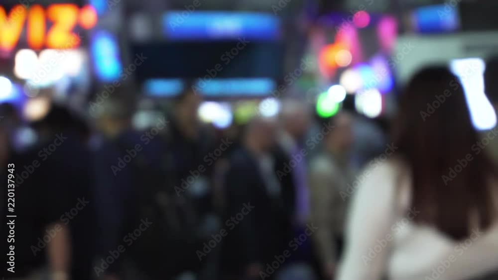 People walking on a convention floor out of focus, in slow motion