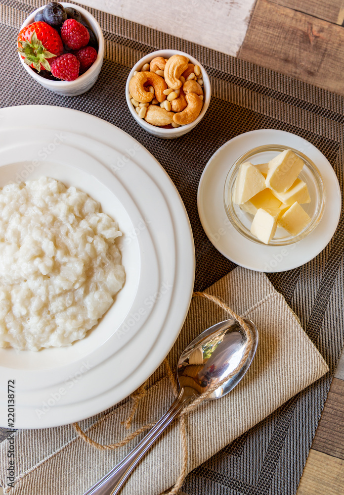 Healthy breakfast. Rice porridge bowl with berries and nuts on the table, hot and healthy breakfast food, top view