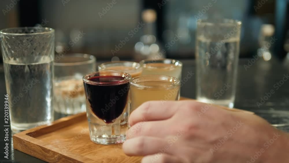 Friends taking shots hands of alcohol together at a nightclub, top view hand take alcohol group colorful cocktails Friends taking shots hands of alcohol together at a nightclub, top view hand take alcohol group colorful cocktails