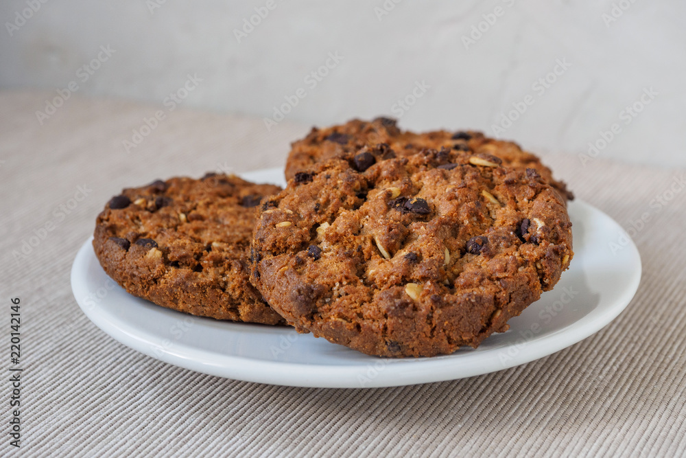 Chocolate chip cookies on white background. Stacked chocolate chip cookies on brown napkin. Symbolic image with place for text. Freshly baked. Concept for a tasty snack. Sweet dessert.