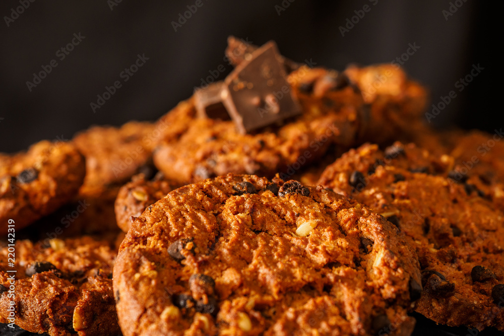 Chocolate chip cookies on rustic dark black background. Stacked chocolate chip cookies on brown napkin. Symbolic image with place for text. Freshly baked. Concept for a tasty snack. Sweet dessert
