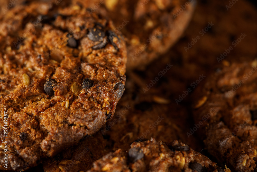 Chocolate chip cookies on rustic dark black background. Stacked chocolate chip cookies on brown napkin. Symbolic image with place for text. Freshly baked. Concept for a tasty snack. Sweet dessert Chocolate chip cookies on rustic dark black background. Stacked chocolate chip cookies on brown napkin. Symbolic image with place for text. Freshly baked. Concept for a tasty snack. Sweet dessert