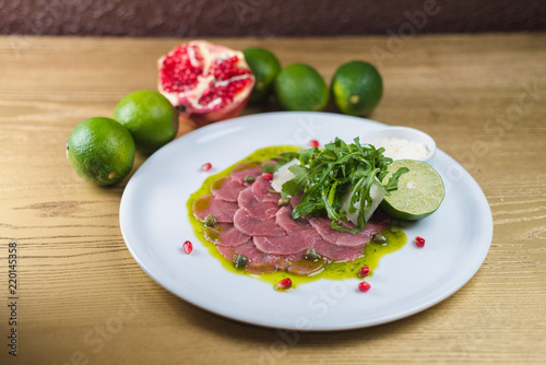 Carpaccio with Parmesan, lime and pesto sauce, on a white plate