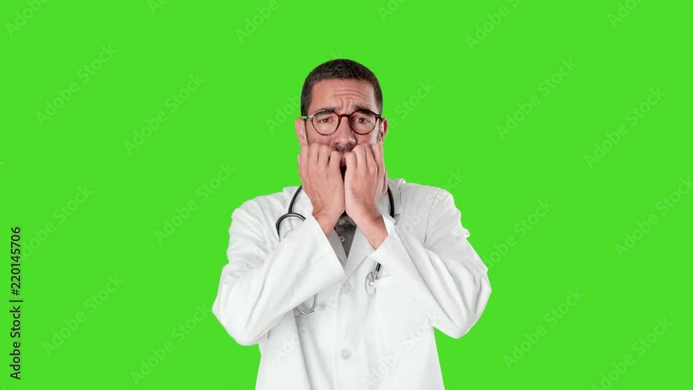 Nervous young doctor biting his nails against green background Nervous young doctor biting his nails against green background