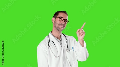 Happy young doctor pointing up against green background