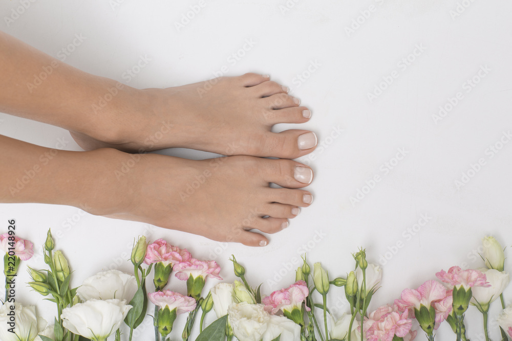 The picture of perfectly done pedicure. Foot surrounded by colorful flowers.