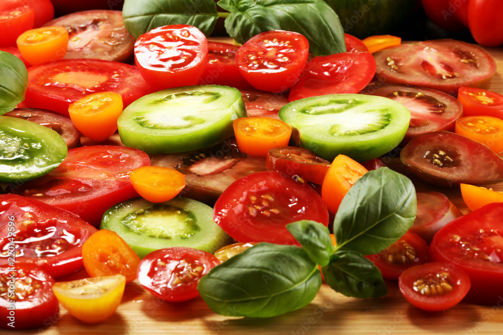 various colorful tomatoes and basil leaves on rustic table. various colorful tomatoes and basil leaves on rustic table.