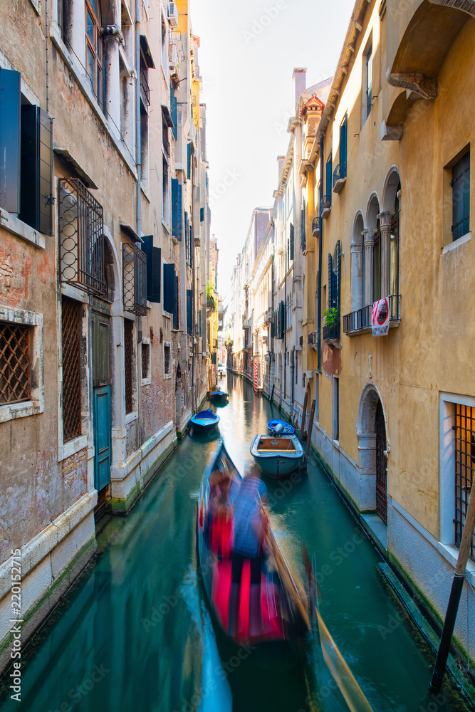 Blurred effect for a gondolier with tourists in a canal in Venice