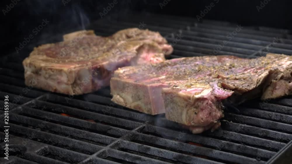 Grilling porterhouse steaks on a gas grill, slow motion Grilling porterhouse steaks on a gas grill, slow motion