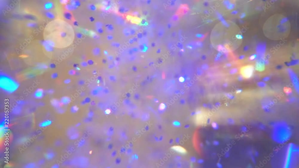 Close up inside a snow globe with blue and teal flakes floating around, in slow motion