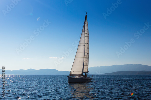 Sailing yacht with white sails in the Sea near Greece coast.
