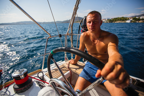 Man skipper runs a sailing yacht on the open sea. © De Visu