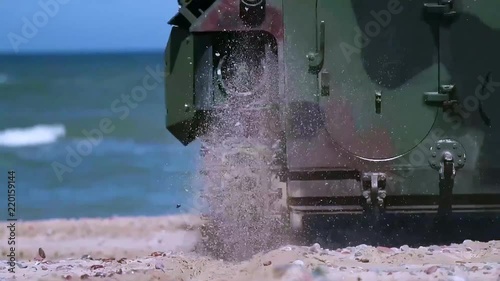 An army amphibious assault vehicle makes its way down a beach and into the ocean.