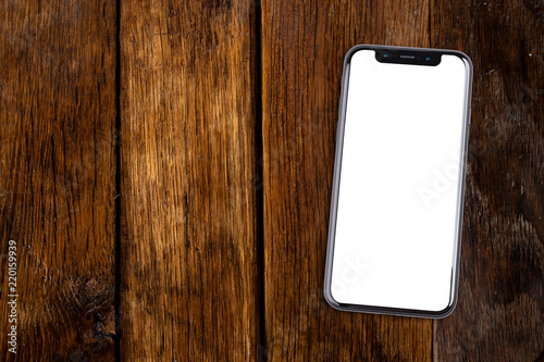Smartphone lies on a wooden table. Isolated white screen with copy space.