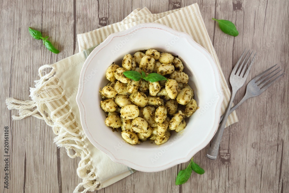 Plate of gnocchi with pesto sauce. Top view over a wooden background. Plate of gnocchi with pesto sauce. Top view over a wooden background.