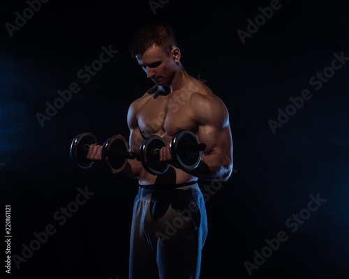 Fitness man on black, posing, with blue smoke on background © honored