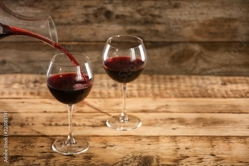 Pouring delicious red wine into glass on table