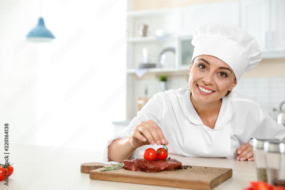 Professional female chef cooking meat on table in kitchen Professional female chef cooking meat on table in kitchen