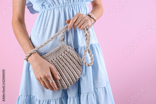 Young woman in stylish outfit with purse on color background, closeup