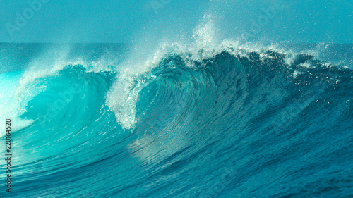 CLOSE UP: Glimmering barrel wave rushes past the camera on a sunny day in Tahiti