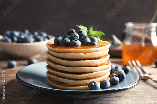 Plate with pancakes and berries on wooden table
