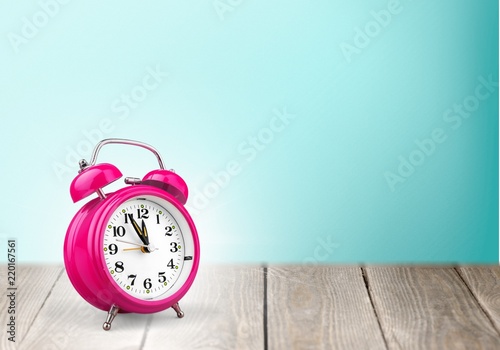Orange retro alarm clock on wooden table on wall background