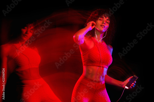 Happy young and fitness woman dancing on black background