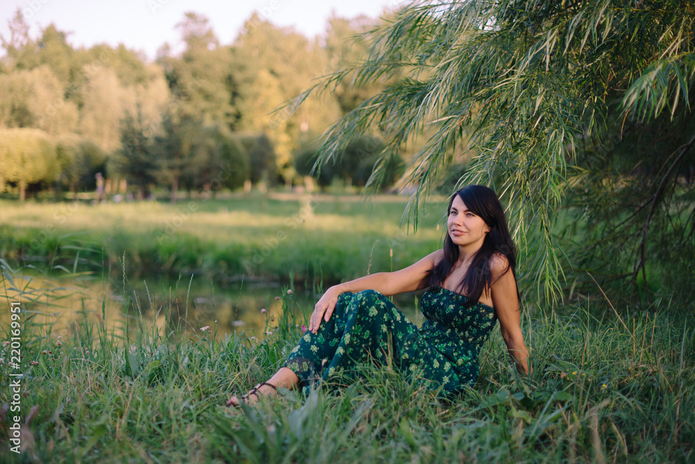 beautiful woman sitting on the grass by the lake