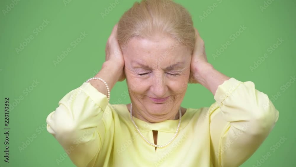 Beautiful senior businesswoman covering ears as three wise monkeys concept Beautiful senior businesswoman covering ears as three wise monkeys concept