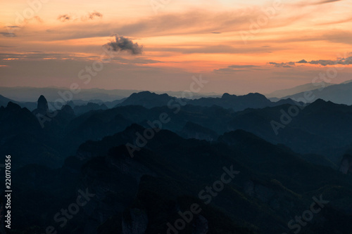 Bajiaozhai National Forest Park in Ziyuan County, Guangxi Province China. Dawn, Orange Sunrise, and Danxia Landform Silhouettes. Rugged Mountains, Danxia Cliffs, Candle Peak in the Distance. Abstract