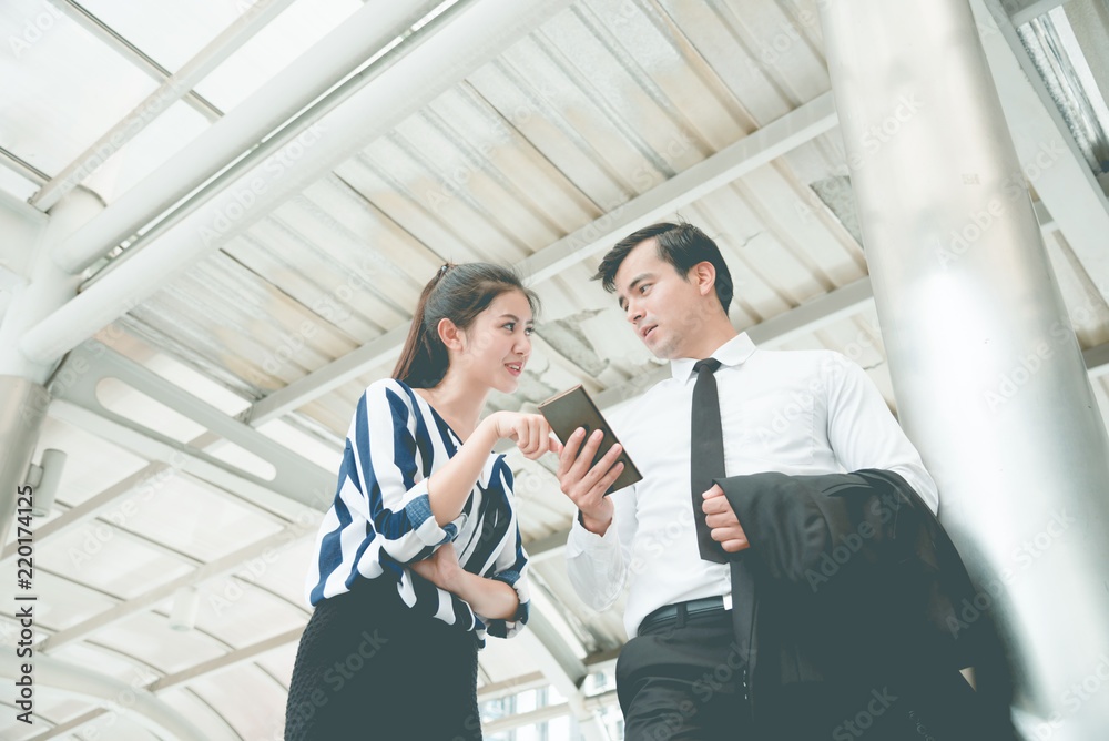 businessman and businesswoman looking at smartphones and discussing for their project businessman and businesswoman looking at smartphones and discussing for their project