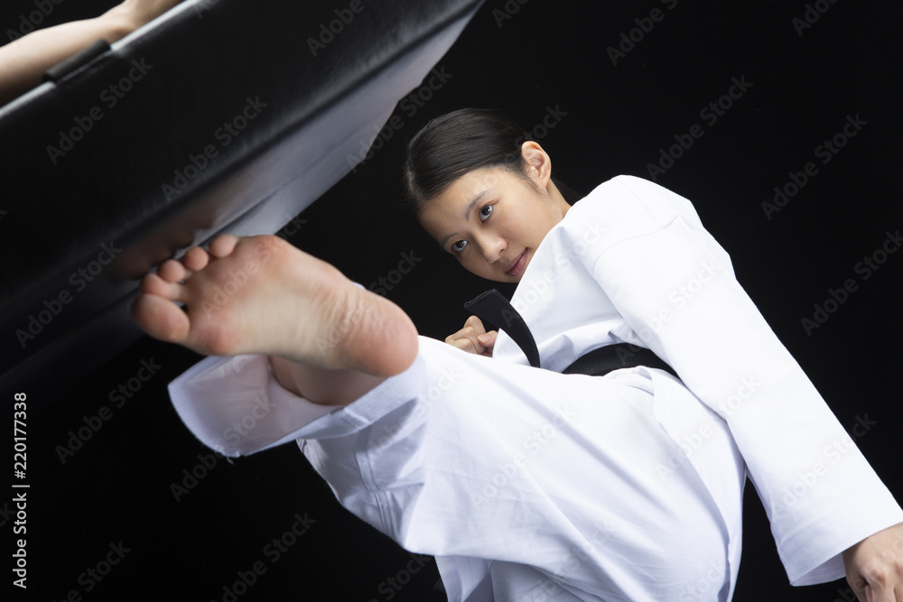 空手着を着てキックミットを蹴る若い女性 Stock Photo Adobe Stock