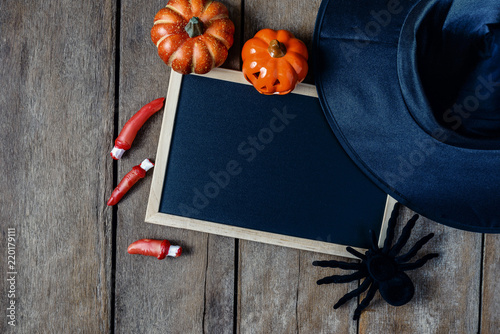 halloween background with Pumpkins, Witch hat, Black spider, fingers and chalkboard on wooden floor background