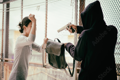 villain is using a gun to rob a bag from a woman. photo