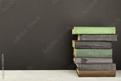 a stack of old books stands on a shelf, a blackboard background.