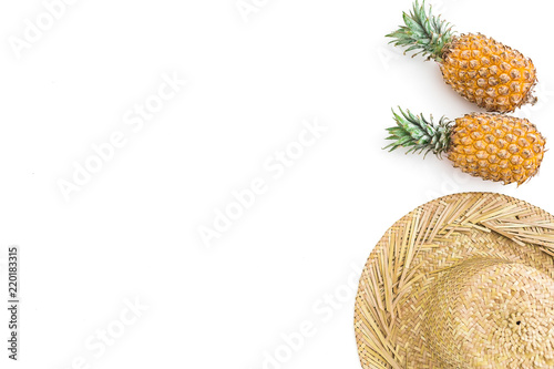 Tropical concept. Pineapple fruits and straw hat on white background. Flat lay, top view.