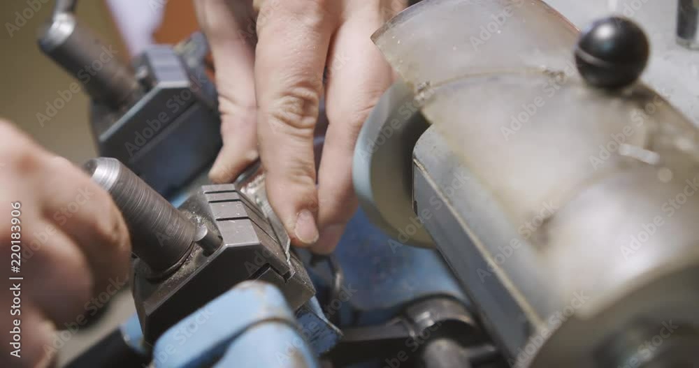 Manufacturing of keys in the workshop. Locksmith sharpen the duplicate of the door key on the grinding machine. Close-up.