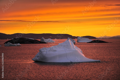 Icebergs in the Greenland Sea are illuminated by a bright light at sunset.